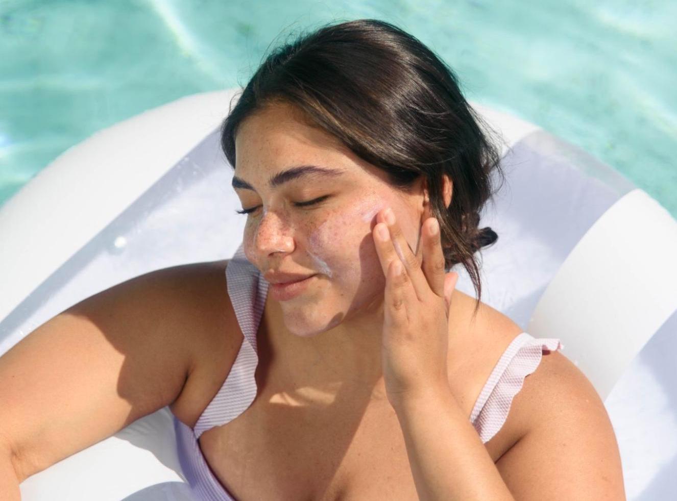 Girl putting sunscreen on her face
